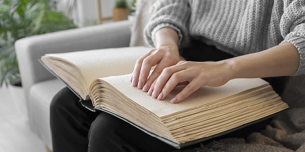 Braille könyv olvasása a kanapén ülve